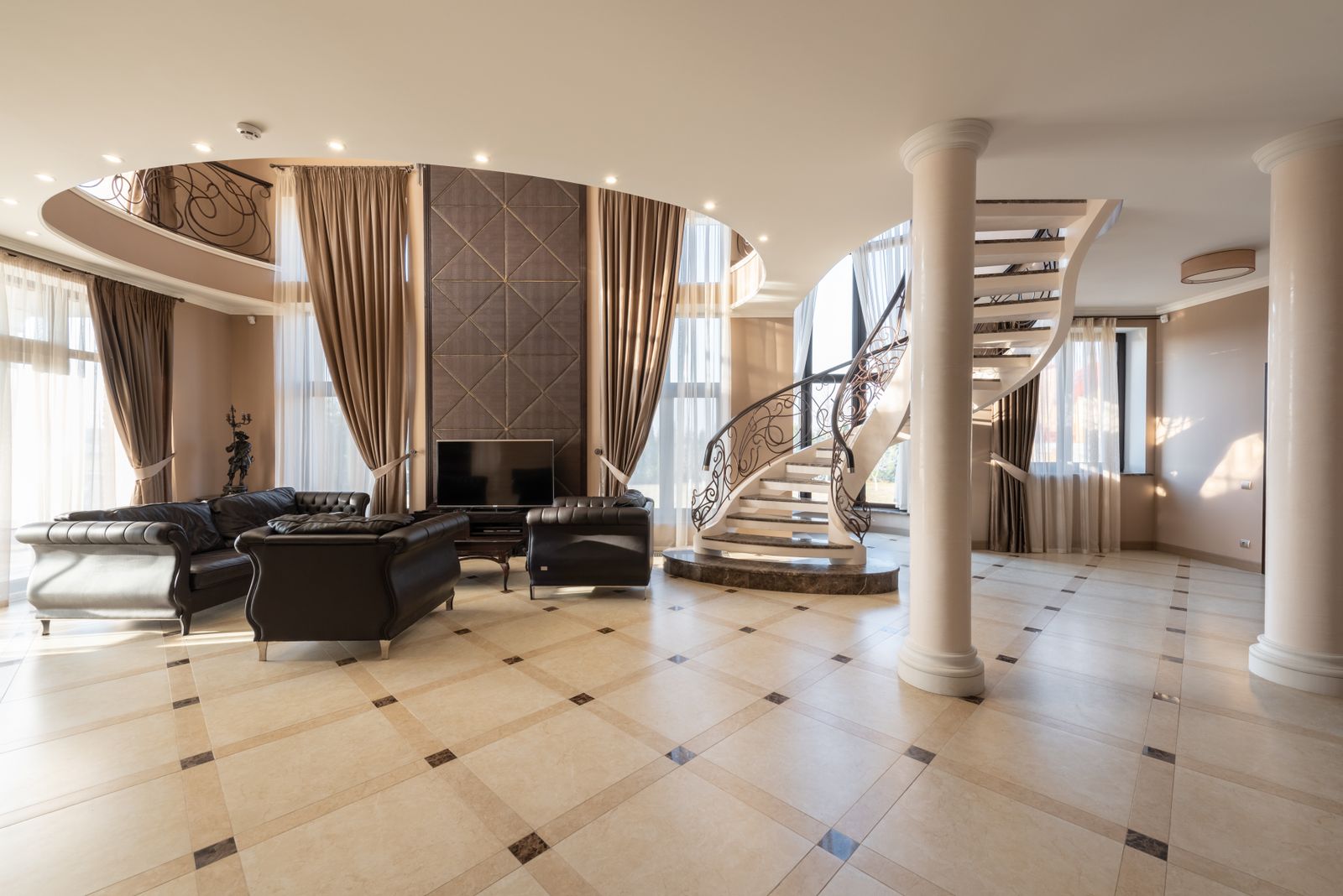Vestíbulo clásico de una villa señorial con columnas y escalera de caracol, idea de palacio privado en alquiler exclusivo en España