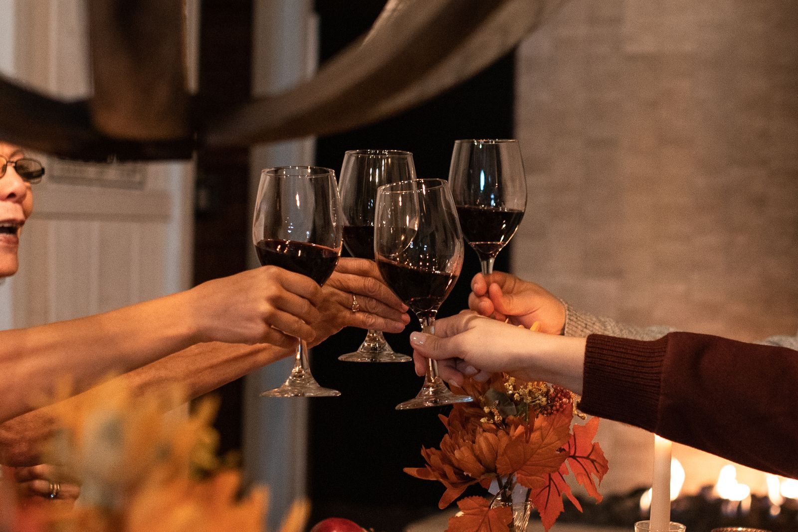 Grupo de amigas brindando con copas de vino tinto en una cena de otoño a la luz de las velas, plan de despedida de soltera tranquila con vino en La Rioja