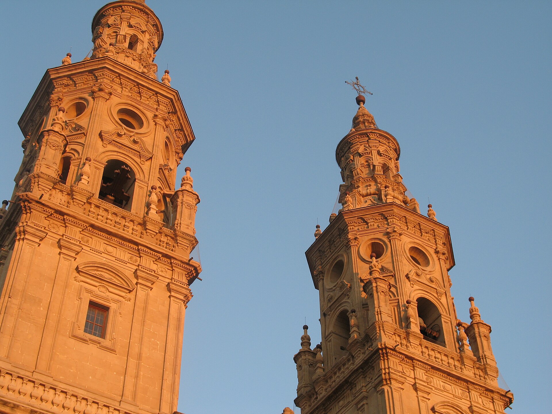 Torres barrocas gemelas de la Concatedral de Santa María de la Redonda en Logroño, iluminadas por el sol del atardecer sobre un cielo azul
