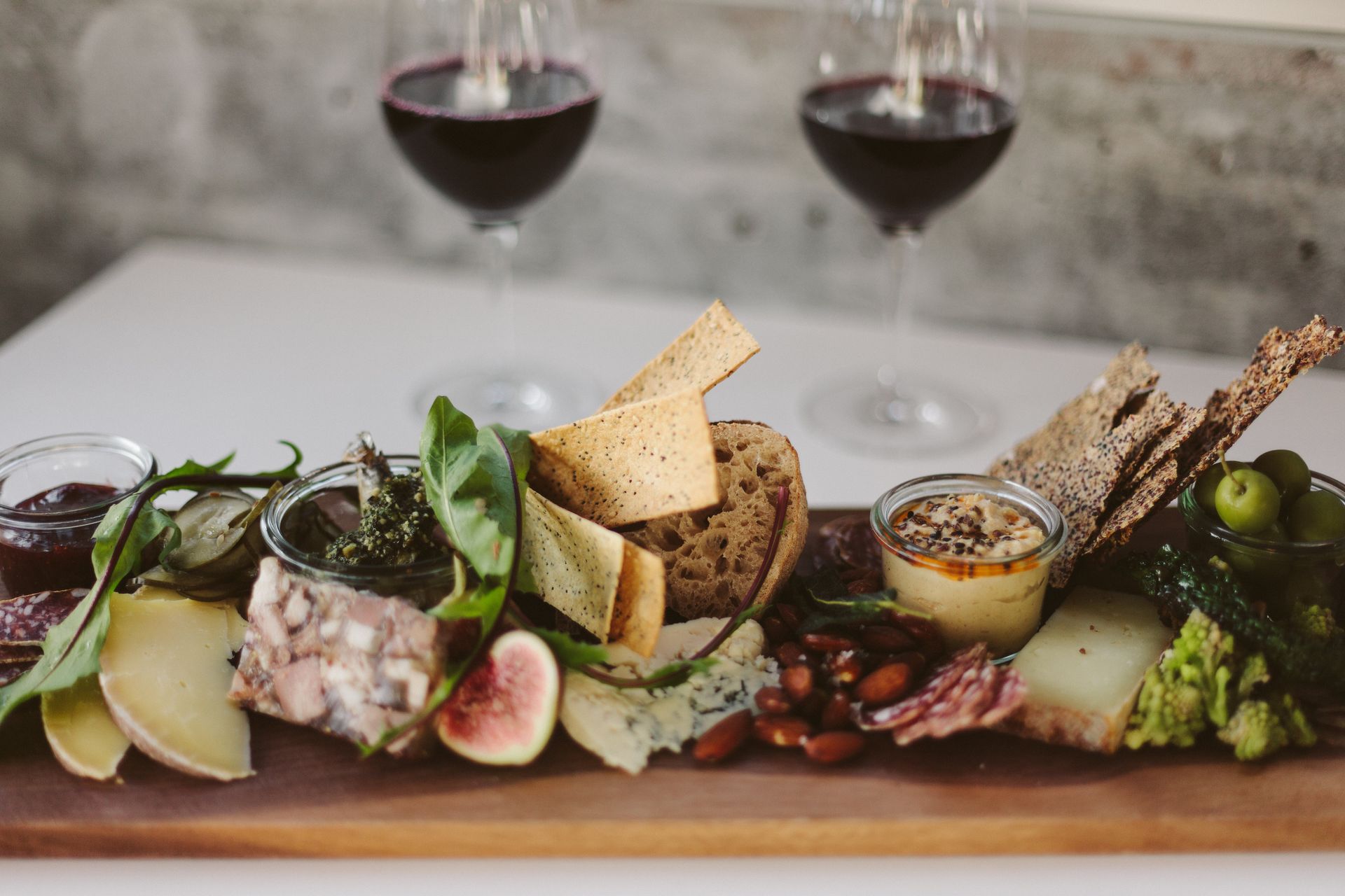 Tabla de quesos, embutido, higos y almendras con dos copas de vino tinto al fondo, un maridaje clásico para un Rioja Crianza o Reserva