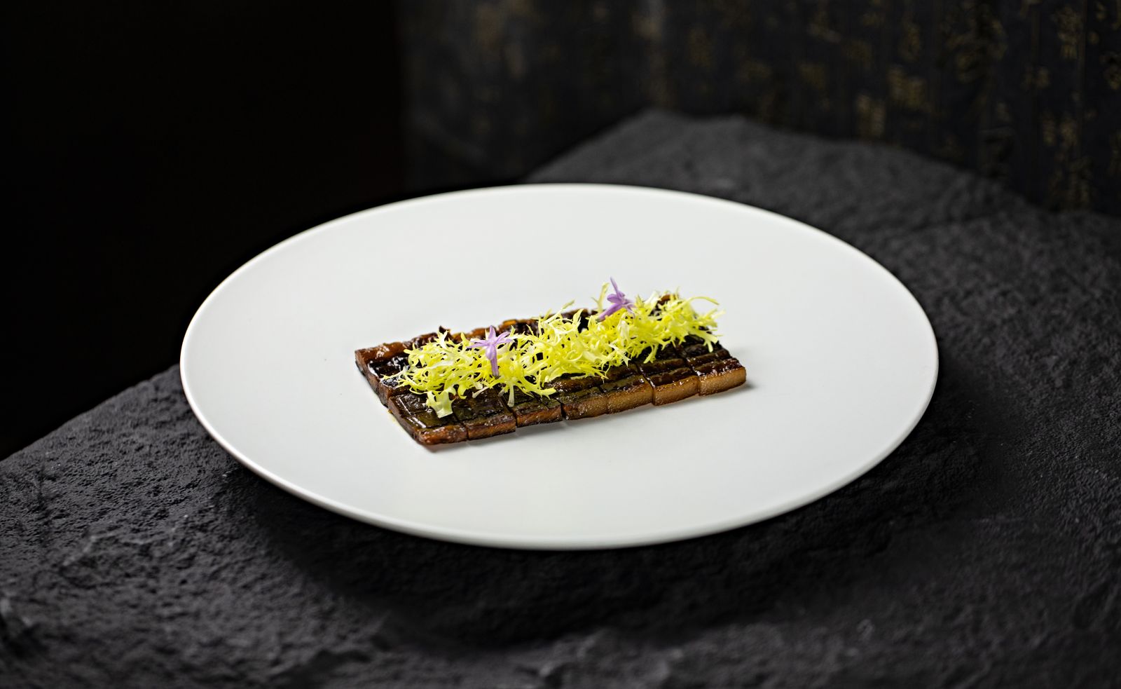Plato de alta cocina con emplatado minimalista sobre loza blanca y piedra oscura, como los de los menús degustación de los restaurantes con estrella Michelin de La Rioja